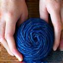 Hands working with natural dyeing materials, vibrant plant-based dyes, and organic yarn.