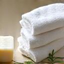 Organic cotton washcloths neatly folded with a natural bar of soap and a small plant, signifying gentle personal care.