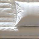 Soft, layered organic bedding with natural light, suggesting comfort and deep sleep.