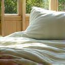 A cozy, naturally lit bedroom with organic linen bedding and soft, muted tones, inviting deep rest