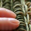 Close-up of hands weaving colorful threads on a small loom, highlighting craft-based mindfulness
